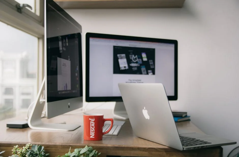 A modern workspace featuring dual computer monitors displaying web design projects, emphasizing technology and productivity.